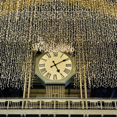 Eine der großen Uhren in der Wandelhalle des Hauptbahnhofs mit weihnachtlichen Lichtern ringsum