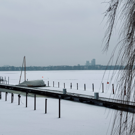 Ein Bootssteg im Eis, ein Segelboot unter eine Plane