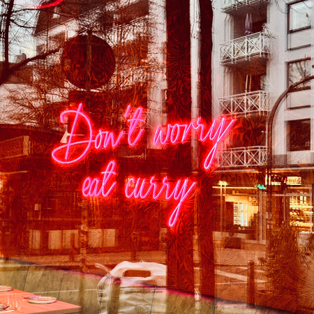 Neonschrift an einer Restaurantwand: Don't worry eat curry