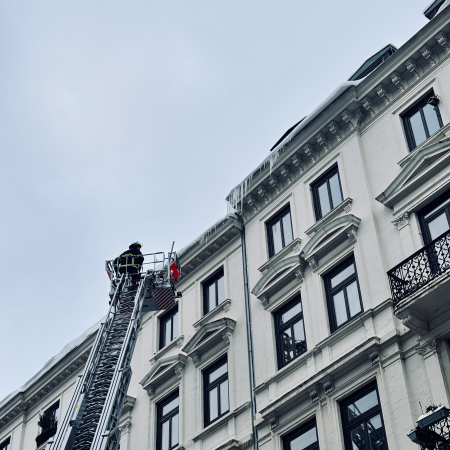 Ein Feuerwehrmann auf einer Drehleiter an einer Dachkante