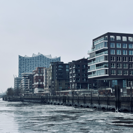 Eine Häuserreihe in der Hafencity, dahinter die Elbphilharmonie