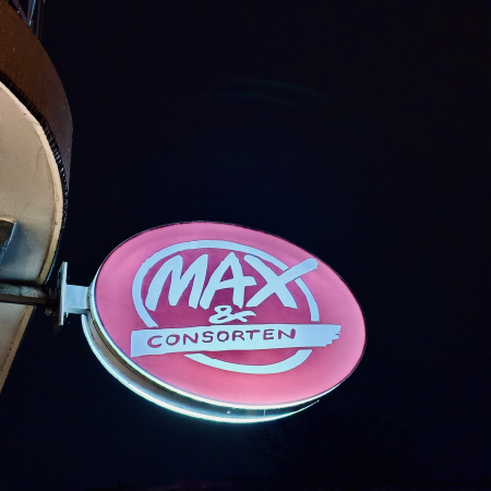 Das beleuchtete Schild einer Kneipe: Max & Consorten