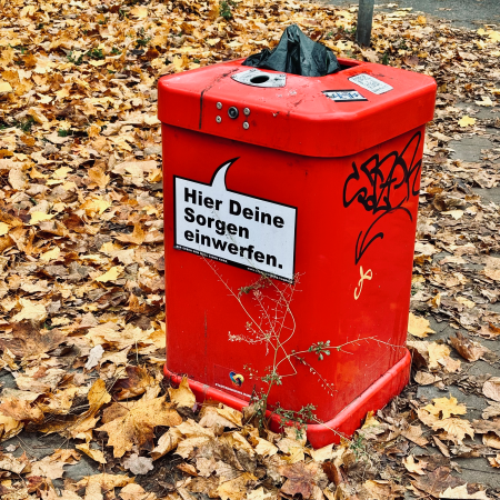 Ein öffentlicher Mülleimer mit Aufkleber: Hier Deine Sorgen einwerfen