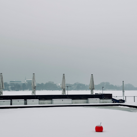 Ein Bootssteg mit zugeklappten Sonnenschirmen an der zugefrorenen Außenalster