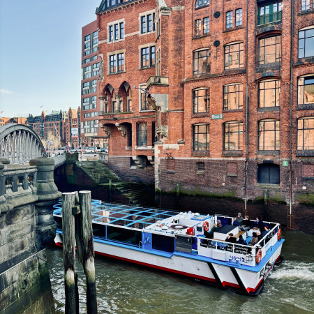 Speicherstadt und Fleet, eine Hafenrundfahrt passiert gerade das Gebäude und eine Brücke