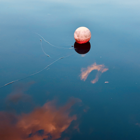 Eine ungemein dekoratov in der Alster treibende Boje auf sehr blauem Wasser mit rosa Wolkenspiegelungen