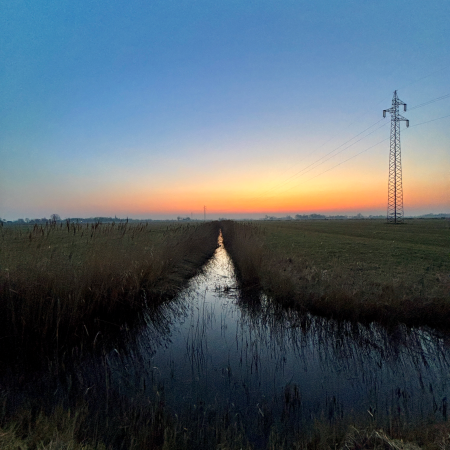 Ein Graben zwischen Fennen im Abendlicht