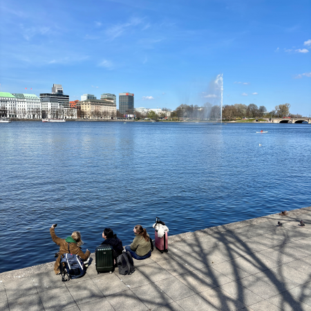 Menschen sitzen an der Ballindammseite am Ufer der Binnenalster