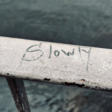 Schrift auf einem Brückengeländer: Slowly