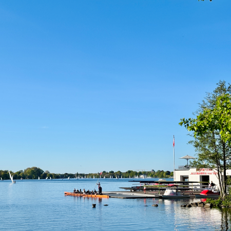 Ein Bootsclub an der Außenalster, Ruderer davor, die gerade in ihr Boot steigen (Achter)