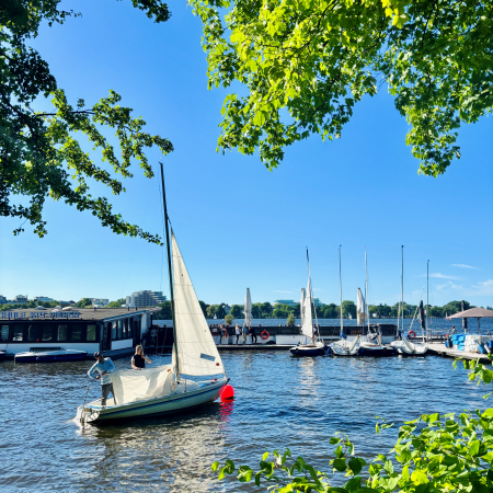 Ein startendes Segelboot vor einem Steg an der Außenalster
