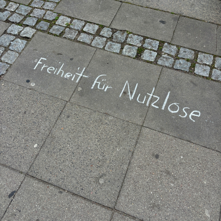 Kreideschrift auf dem Pflaster: Freiheit für Nutzlose
