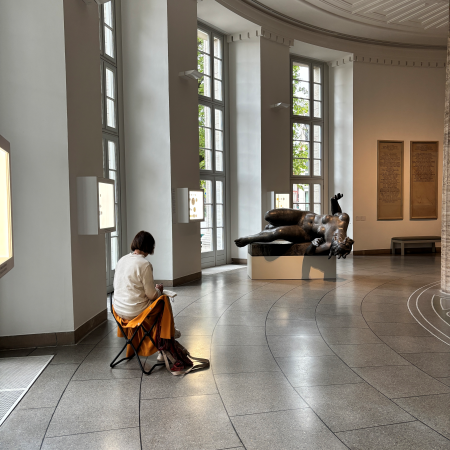 Eine Frau zeichnet eine liegende Figur in der Skulptural-Ausstellung