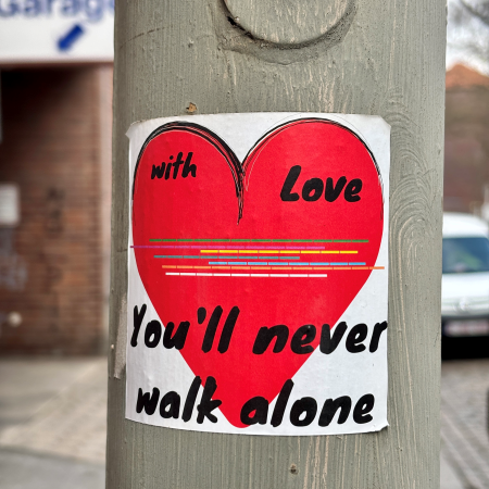 Ein Sticker an einem Laternenmast: With love you'll never walk alone