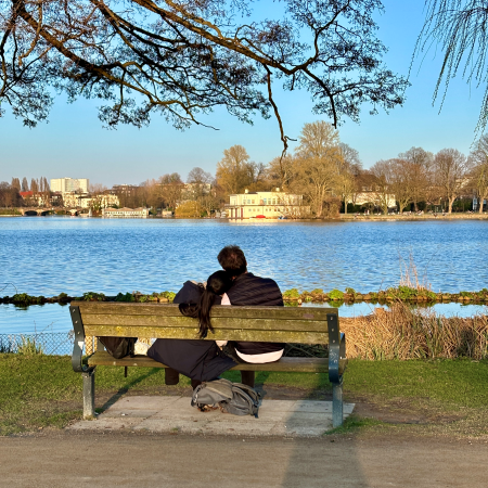 Ein Paar auf einer Bank am Ufer der Außenalster, von hinten aufgenommen