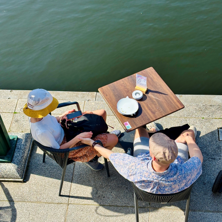 Blick von oben auf einen Tishc des Café Rathauismarktpassage an der Kleinen Alster, direkt am Wasser stehend