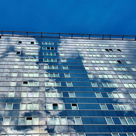 Blauen Himmel spiegelnde gläserne Hochhausfassaden