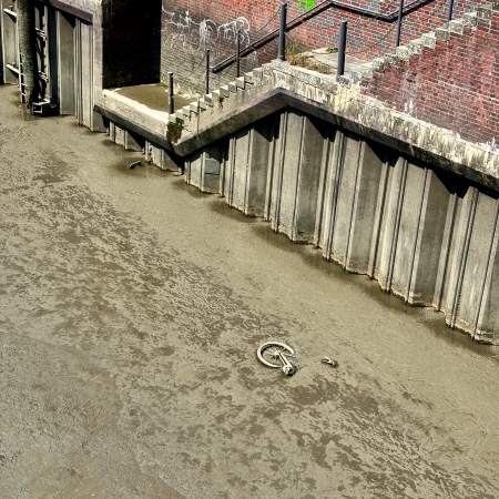 Ein Fleet bei Niedrigwasser, im Schlamm wird ein versunkenes Fahrrad erkennbar