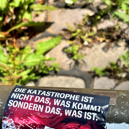 Ein Sticker: Die Katastrophe ist nicht das, was kommt, sondern das, was ist.