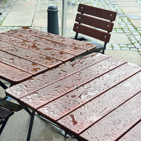 Regen auf Stühlen und Tisch in der Außengastro