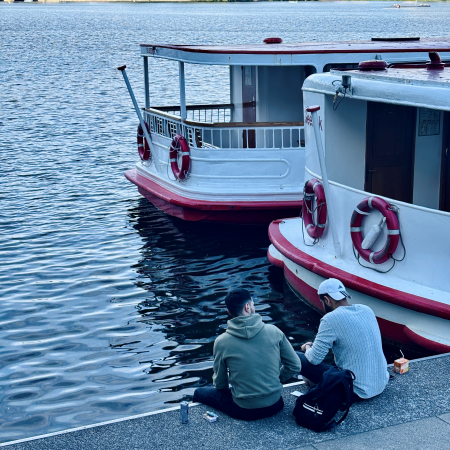 Boote der Weißen Flotte am Anlager Jungfernstieg, Menschen sitzen an der Kaikante