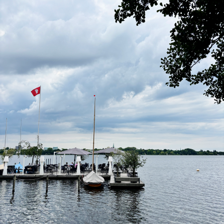 Ein Steg mit Aiußengastro auf der Außenalster, bedeckter Himmel