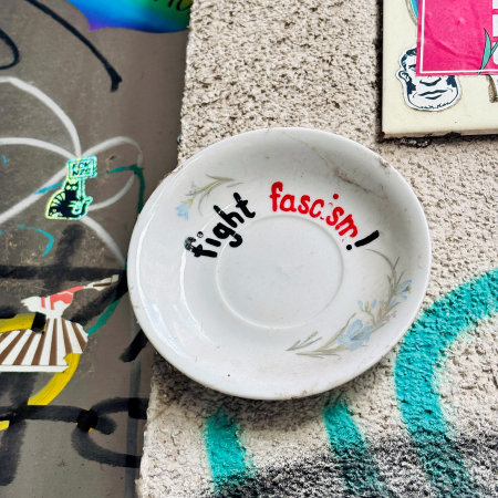 "Fight Fascism" steht auf einem Porzellanteller, der an einer Wand klebt