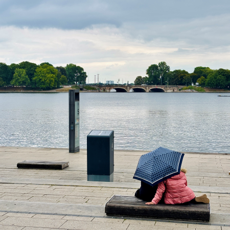 Blick über die Binnenalster bei Regen, vom Jungfernstieg aus, im Vordergrund ein Paar, unter einem Regenschirm auf einer Bank sitzend