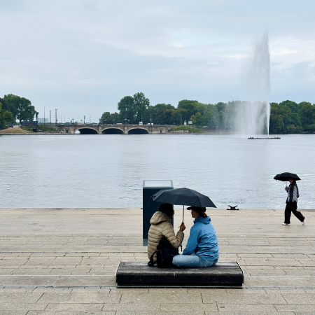 Blick über die Binnenalster vom Jungfernstieg aus, im Vordergrund Menschen unter Regenschirmen