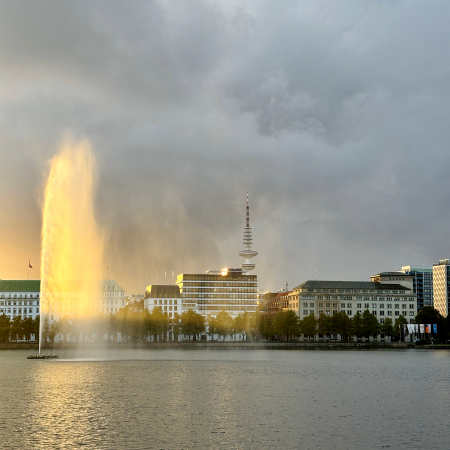 Die Fontäne auf der Binnenalster leuchtet in der Abendsonne auf