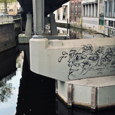Graffiti an einem Brückenpfeiler, ein Kopf in vielen versetzten Teilen abgebildet