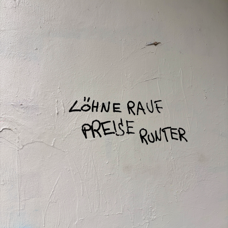 Schrift an einer Wand. "Löhne rauf, Preise runter"