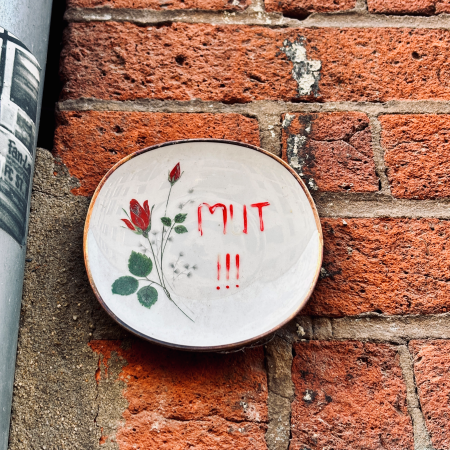 Ein an einer Wand hängender Teller, auf dem "Mut!" steht