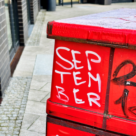 Das Wort September wurde in weißer Farbe auf einen roten Mülleimer geschrieben
