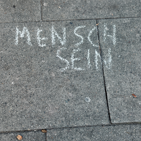 Kreide auf Pflaster: "Mensch sein"